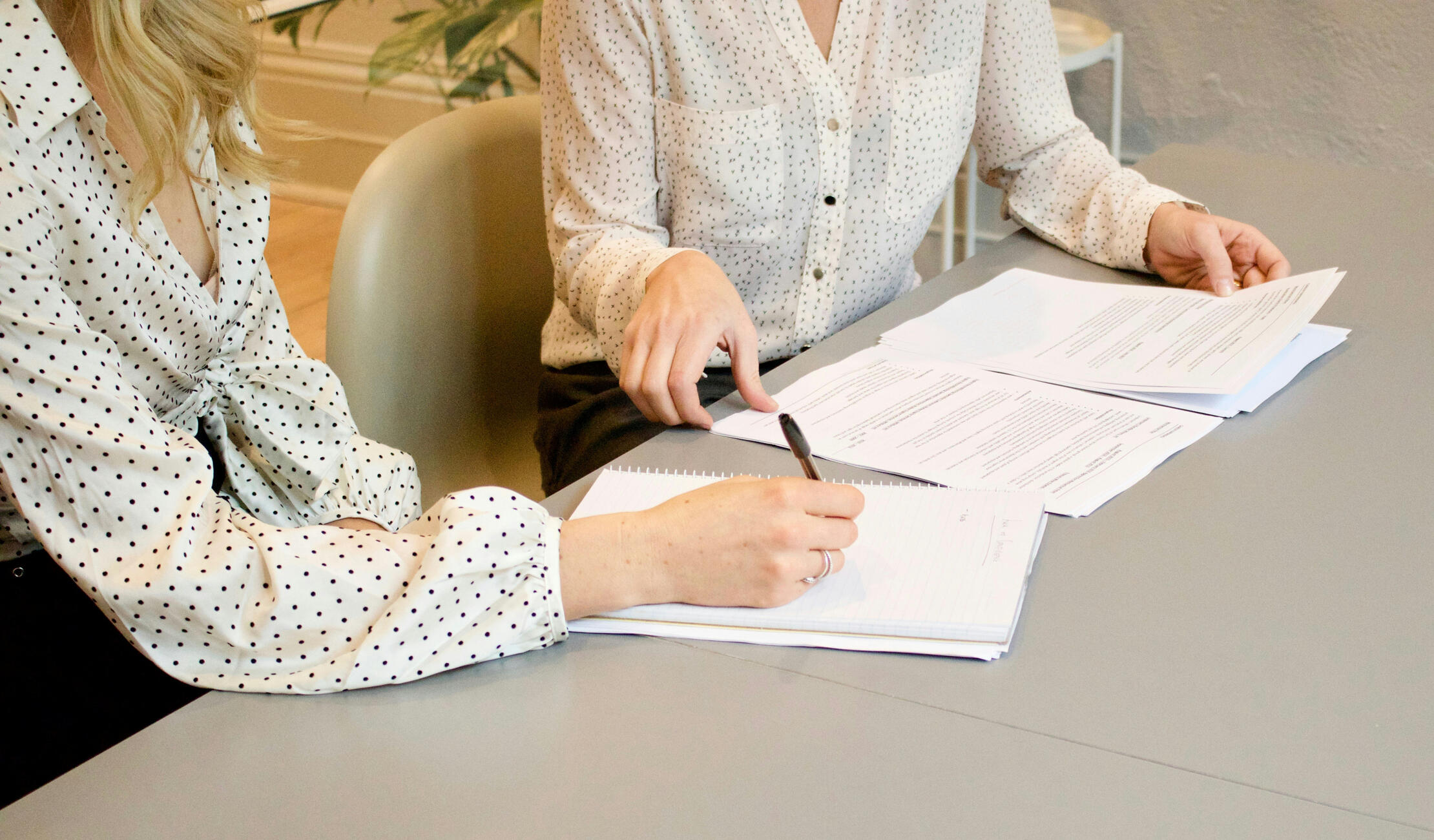 Contact main page Two at a desk taking notes.